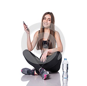 Portrait of a young athlete woman listening to music with earphones over white background. Attractive fitness girl chatting