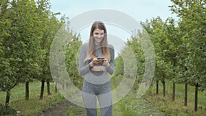 Portrait of a young athletic fitness girl holding a phone in her hands. Shooting on the street on the pyrode between the