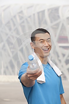 Portrait of young athletic man in Beijing pointing water bottle