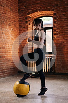 Portrait of young athletic woman with strong beautiful body in sportswear exercising with heavy medicine ball during