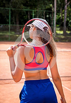 Portrait of young athletic woman on tennis court.