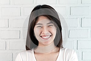 Portrait of young attractive asian brunette woman looking at camera smiling with confident and positve lifestyle concept on brick