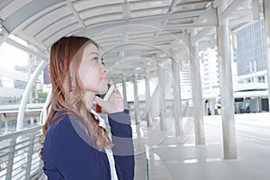 Portrait of young attractive Asian business woman talking on phone for his work at sidewalk of city background.