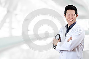 Portrait of young attractive asian doctor or physician man crossed arms holding stethoscope medical equipment