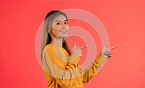 Portrait of young attractive asian girl pointing on side