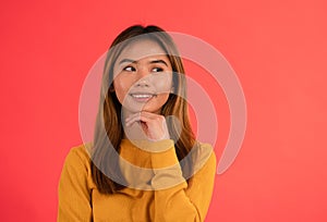 Portrait of young attractive asian girl smiling while thinking with hands on chin