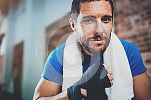 Portrait of Young attractive athlete tying black boxing bandages.Boxer man prepairing before kickboxing training