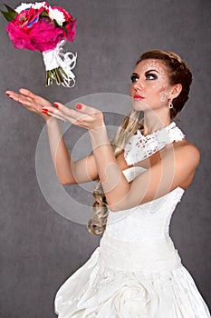 Portrait of a young attractive bride throwing a bunch of flowers