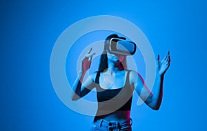 Portrait of young attractive brunette woman in a black top with a virtual reality goggles forehead. VR headset. Virtual