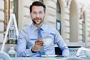 Portrait of young attractive businessman sitting in cafe while drinking coffee