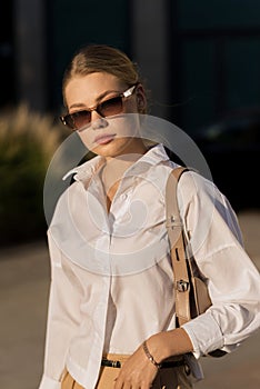 Portrait of a young and attractive Caucasian woman in casual clothes and sunglasses while walking around the city. The concept of