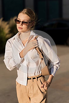 Portrait of a young and attractive Caucasian woman in casual clothes and sunglasses while walking around the city. The concept of