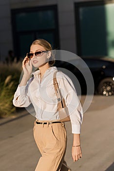 Portrait of a young and attractive Caucasian woman in casual clothes and sunglasses while walking around the city. The concept of