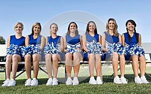 Portrait of young attractive Cheerleading Squad Sitting on Bench