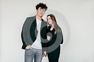 Portrait of young attractive dark-haired curly man and long haired woman in black outfit, sanding close. Copy space