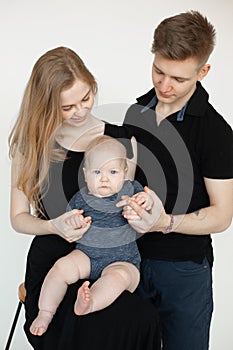 Portrait of young attractive family in dark clothes with plump cherubic baby infant toddler stand on white background.