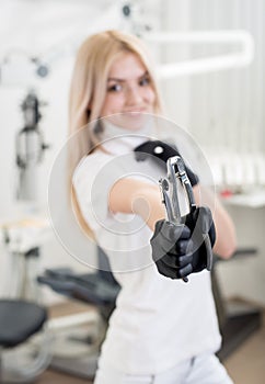 Portrait of young attractive female dentist holding dental tool at the modern dental office