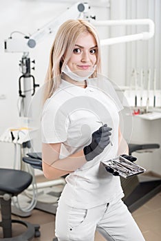 Portrait of young attractive female dentist holding dental tool at the modern dental office