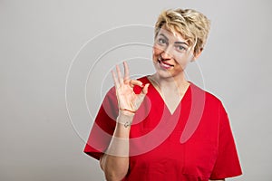 Portrait of young attractive female nurse showing ok gesture