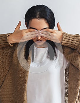 Portrait of young attractive girl covering her eyes with two palms. Beautiful brunette woman closing eyes with hands. I can`t see