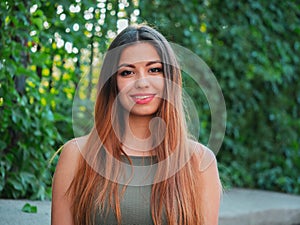 Portrait of young attractive girl looks into the camera with smile. Woman with oriental face, brown eyes and stylish