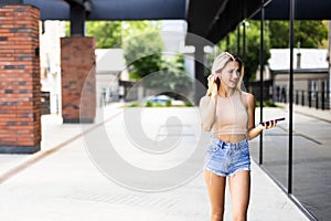 Portrait of young attractive woman in urban background listening to music with headphones
