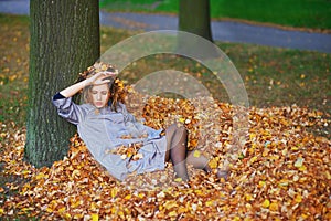 Portrait of young attractive girl with yellow leaves in her hair on autumn background.