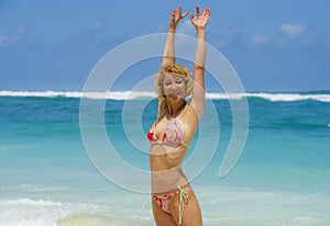 Portrait of young attractive and happy woman in bikini posing at amazing beautiful desert beach raising arms free enjoying Summe