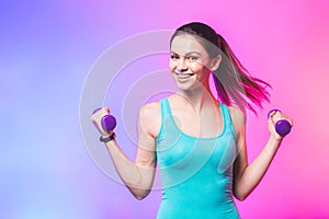 Portrait of young attractive happy woman in sport clothes with beautiful smile holding weight dumbbell doing fitness workout