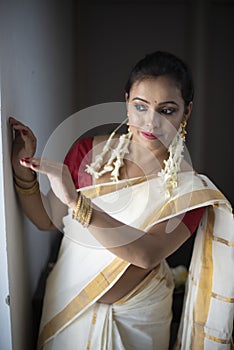 Portrait of an young and attractive Indian woman in white traditional wear for the celebration of Onam/Pongal