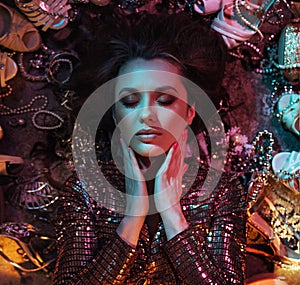 Portrait of a young, attractive lady laying among lots of shoes