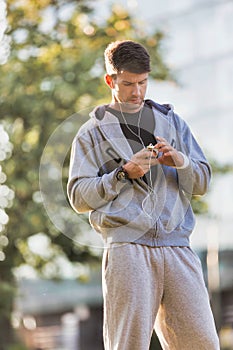 Portrait of young attractive man listening to music with earphones on in park