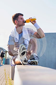 Portrait of young attractive man sitting while drinking energy drink