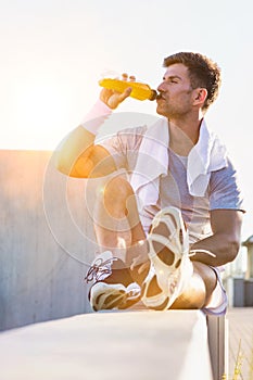 Portrait of young attractive man sitting while drinking energy drink
