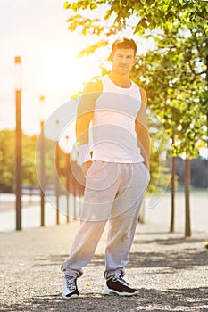 Portrait of young attractive man wearing sports wear standing in park