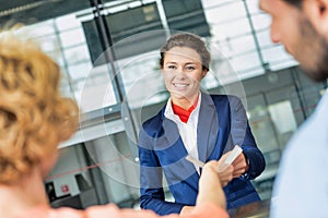 Portrait of young attractive passenger service agent giving boarding with passenger after check in at airport