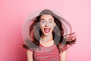 Portrait of young attractive smiling excited shocked girl open mouth flying hair isolated on pink color background