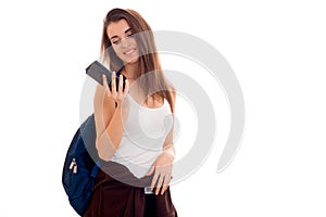 Portrait of young attractive student girl with blue backpack and mobile phone in hands isolated on white background