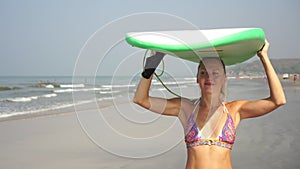 Portrait of a young attractive surfer woman on the beach with a surfboard