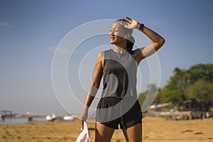 Portrait of young attractive and sweaty happy Asian Indonesian woman in her 40s smiling satisfied after hard beach running workout