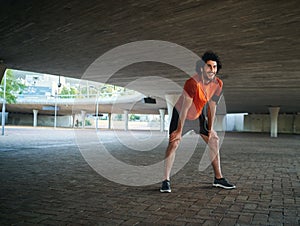 Portrait of young attractive tired man exhausted after outdoors running workout on city street under the concrete bridge