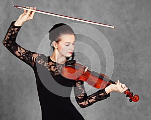 Portrait of a young attractive violinist woman in a black evening dress