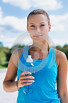 Portrait of young attractive woman drinking energy drink in park