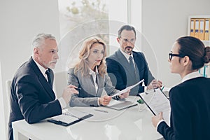 Portrait of young attractive woman in glasses having job interview with three stylish business persons in financial