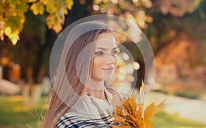 Portrait of an young attractive woman with long blonde hair enjoying her time in the autumn park with yellow trees in background