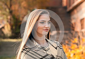 Portrait of an young attractive woman with long blonde hair enjoying her time in the autumn park with yellow trees in background