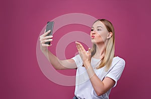 Portrait of a young attractive woman making selfie photo on smartphone isolated.