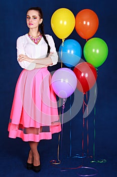 Portrait of a young attractive woman near many bright balloons