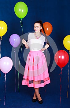 Portrait of a young attractive woman near many bright balloons