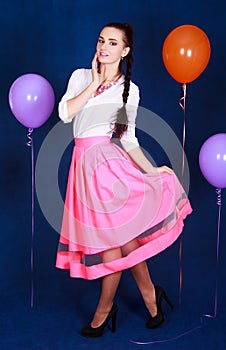 Portrait of a young attractive woman near many bright balloons